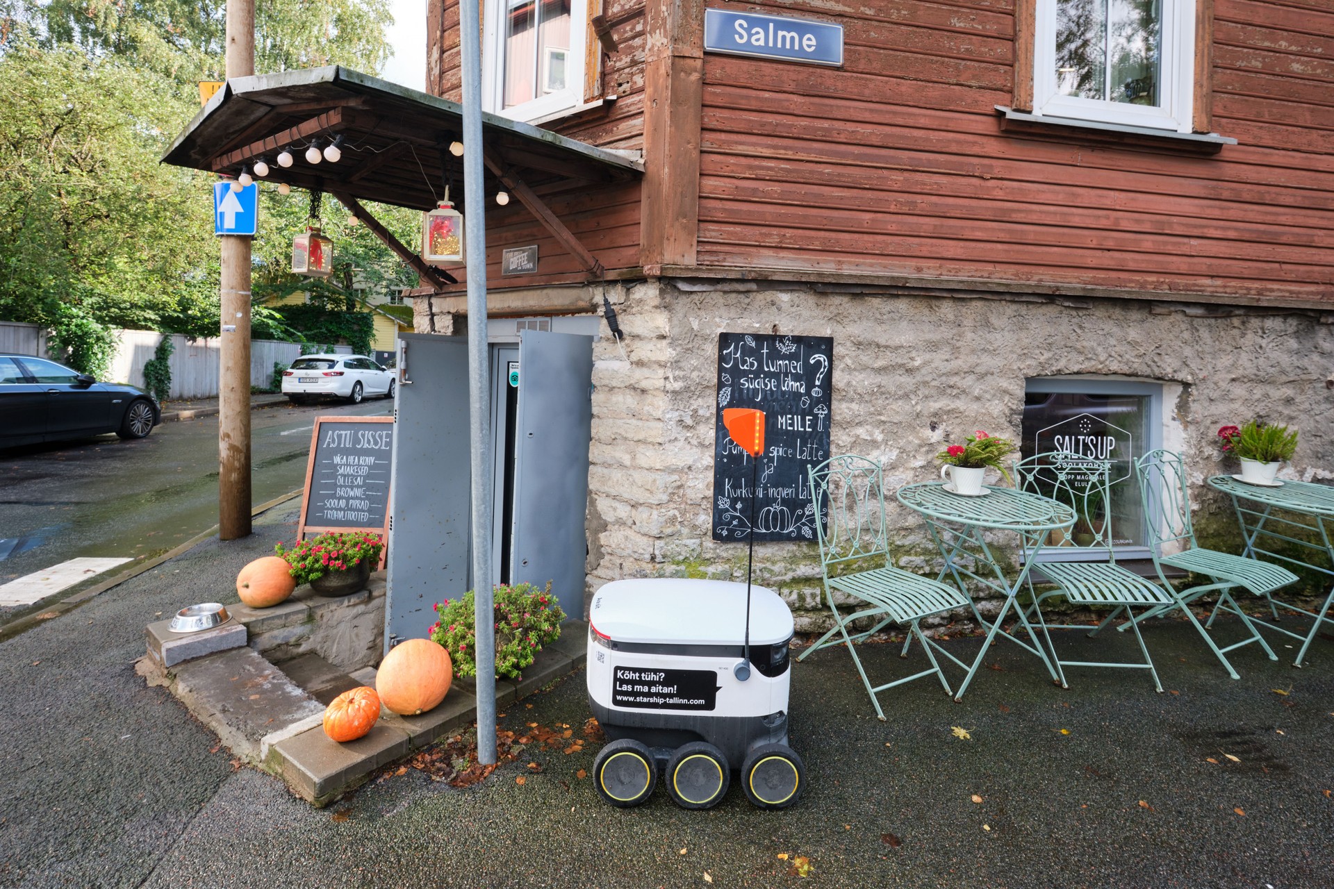 A small post delivery robot sitting outside of a restaurant